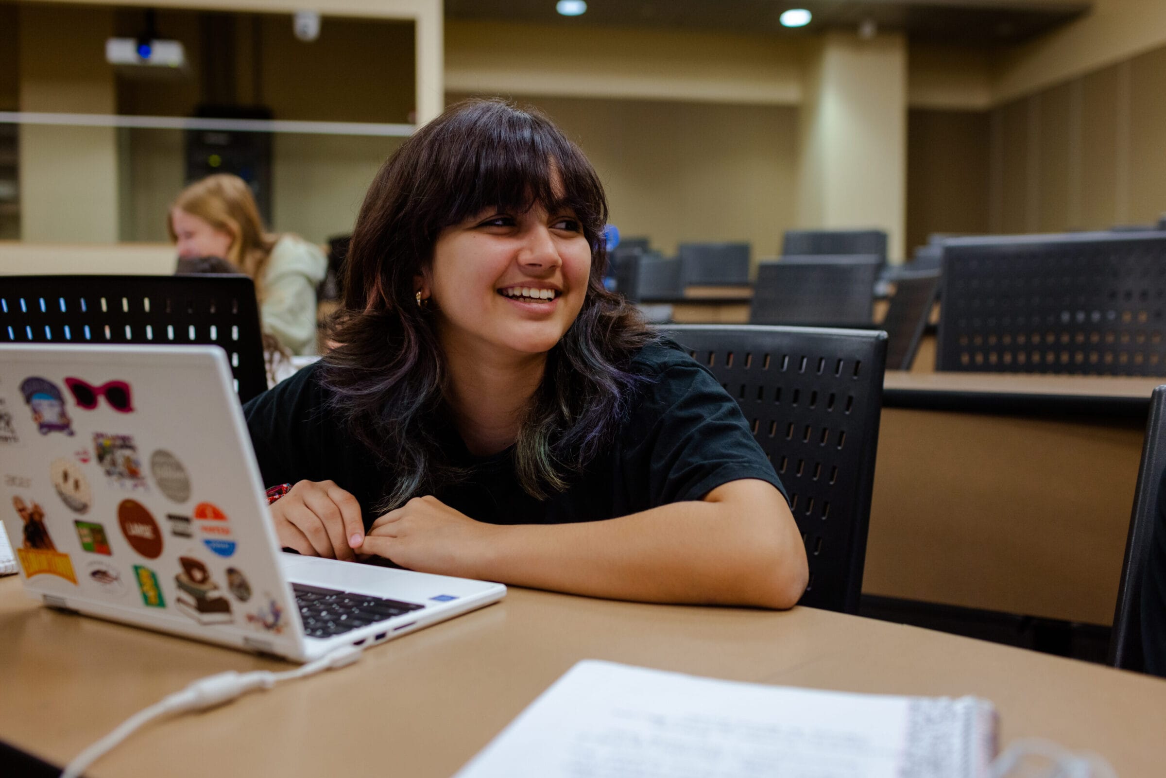 A student smiling as she works on her laptop