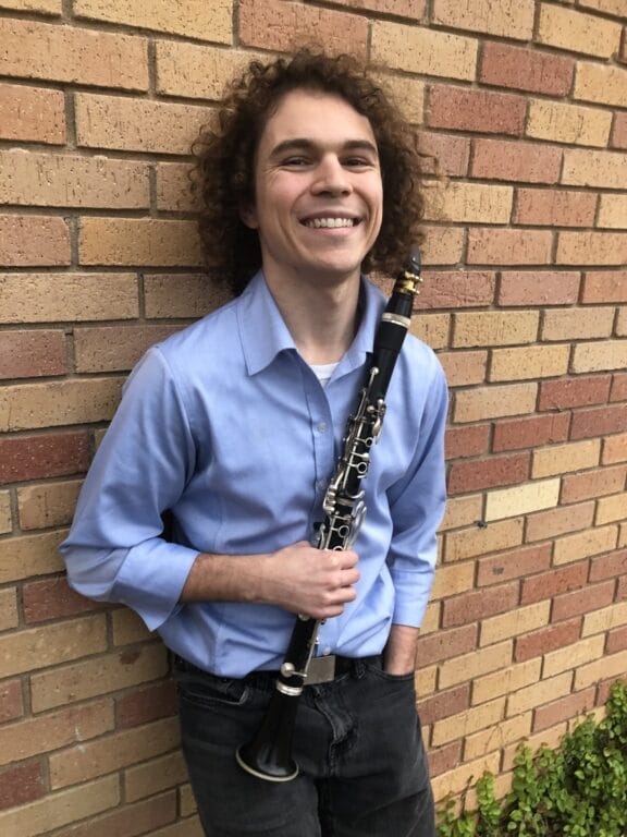 A picture of a young man posing for a picture while holding a clarinet