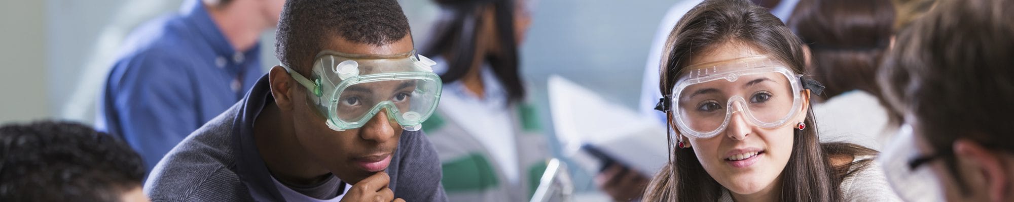 High school students are doing a chemistry experiment in class. The students are all wearing protective safety goggles..