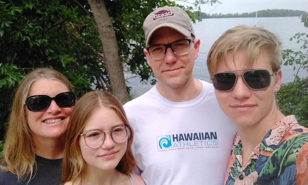 The four members of the Carlson-Colton family pose with a lake behind them in the distance.