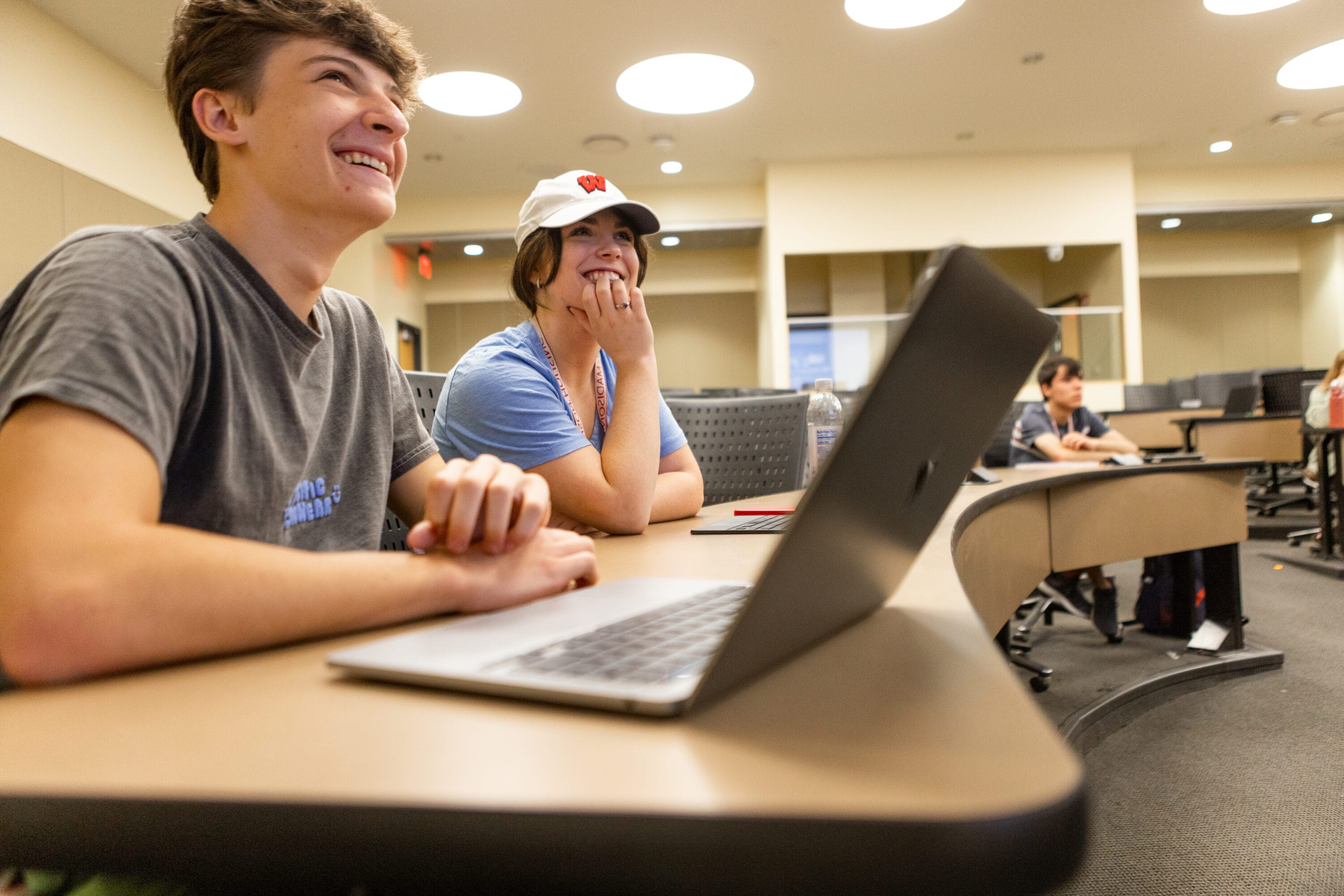 Two students in a UW-Madison classroom working on their laptops