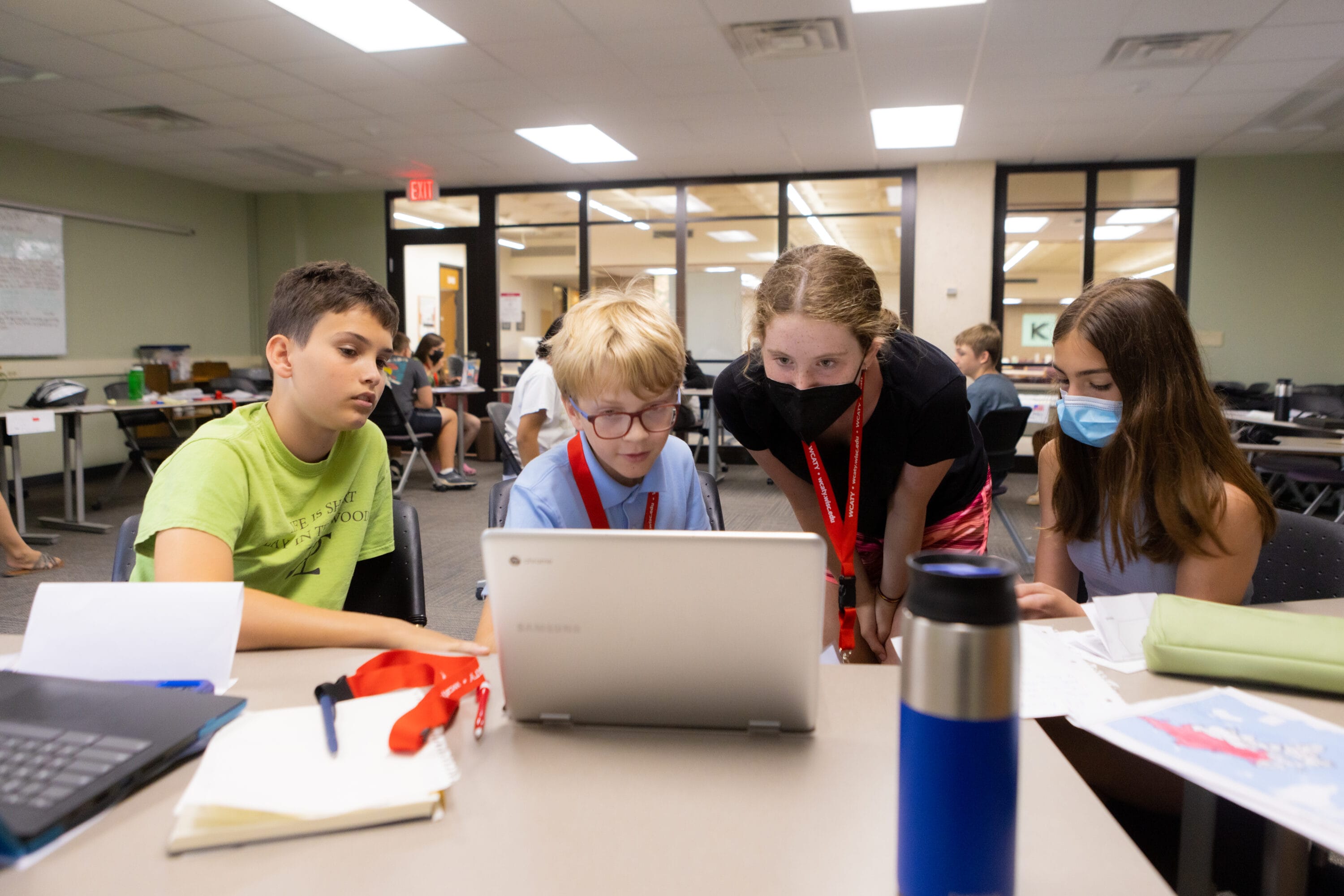 Four Precollege students looking at a computer.