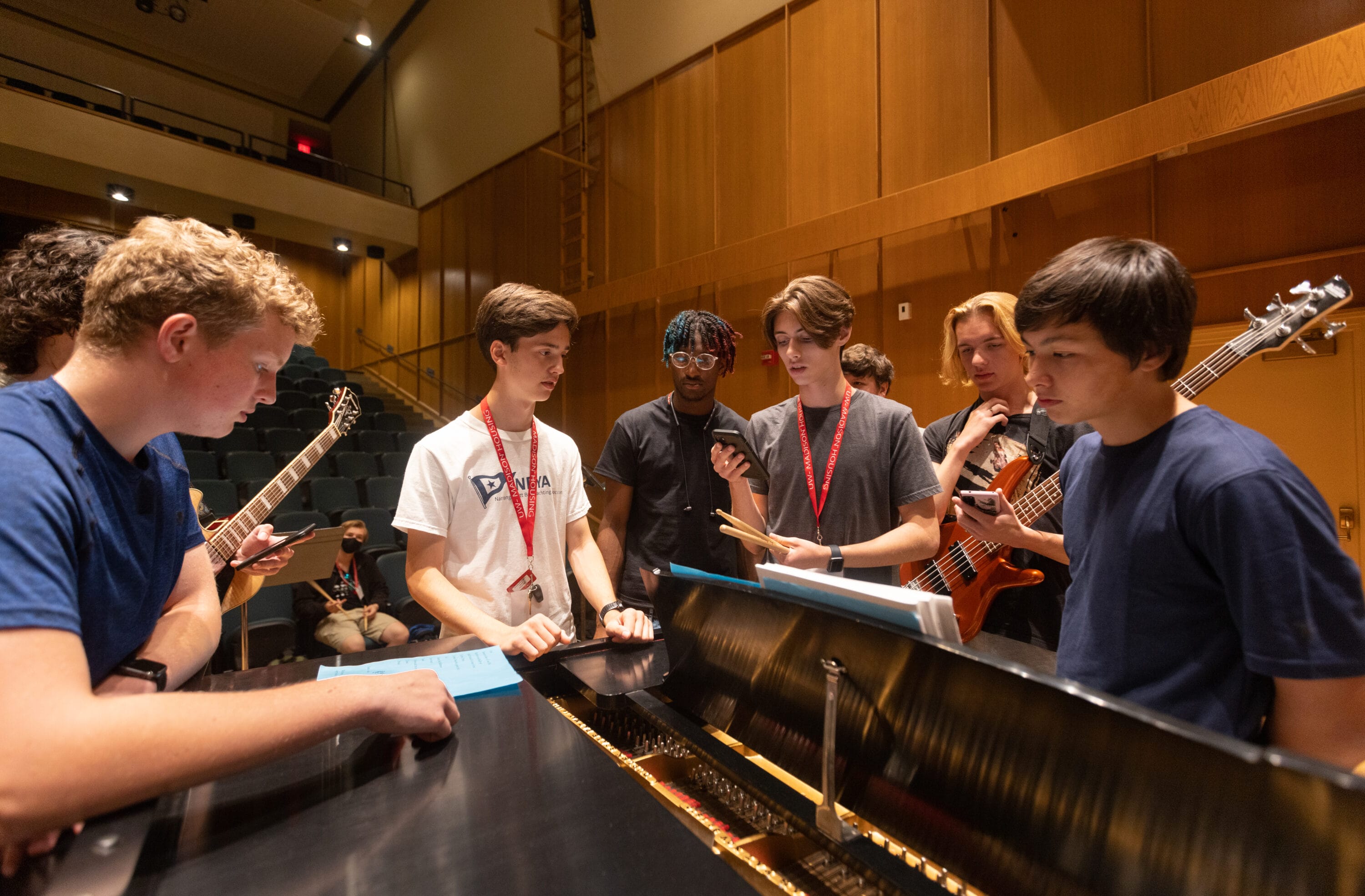 A group of music students around a piano.