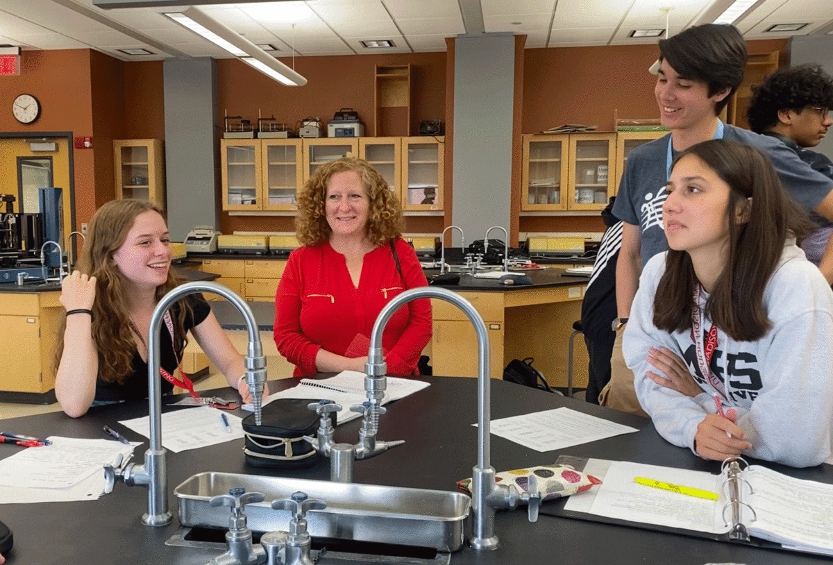 chancellor mnookin standing behind a lab table, talking with students in a classroom